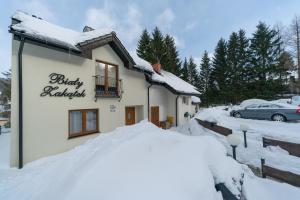 a building covered in snow with a sign on it at Biały Zakątek in Szklarska Poręba