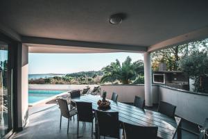 Un patio con mesa y sillas y una piscina. en Villa Sunrise Premantura Sea View, en Premantura