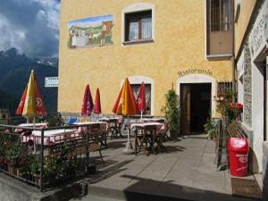 ein Restaurant mit Tischen und Sonnenschirmen vor einem Gebäude in der Unterkunft Albergo Eden in Ponte di Legno
