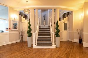 una escalera en una habitación con columnas blancas y plantas verdes en Sandhills Apartments, Mudeford en Christchurch