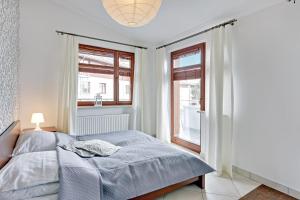 a bedroom with a bed and two windows at Grand Apartments - Neptun Park. in Gdańsk