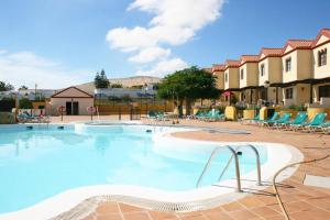 una piscina en un complejo con sillas en Vacation House La Cebada, en Costa Calma