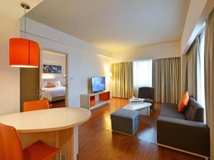 een woonkamer met een tafel en een kamer met een bed bij HARRIS Hotel & Conventions Ciumbuleuit - Bandung in Bandung