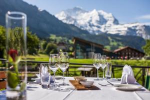 a table with wine glasses on a table with mountains at Hotel Schönegg in Wengen