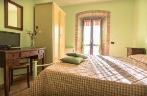 a bedroom with a bed and a desk and a television at Agriturismo Il Giardino Dei Ciliegi in Passaggio Di Assisi