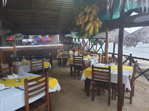 un restaurante con mesas, sillas y plátanos colgando del techo en Tropical Paradise Nosy Be, en Nosy Be