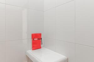 een rode tas bovenop een toilet in een kamer bij KoolKost Syariah near Ayani Mega Mall Pontianak in Pontianak