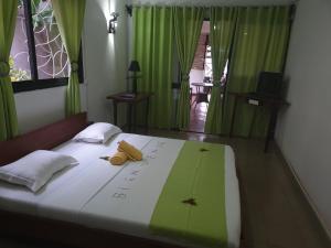 a bedroom with a bed with green and white sheets at Tropical Paradise Nosy Be in Nosy Be