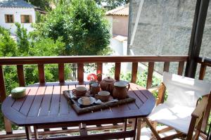 drewniany stół z kubkami i miskami na balkonie w obiekcie Mirto Apartments w mieście Afissos +36 zdjęć