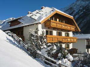 ein schneebedecktes Haus mit einem Holzbalkon im Schnee in der Unterkunft Frühstückspension Rehwinkl in Sölden
