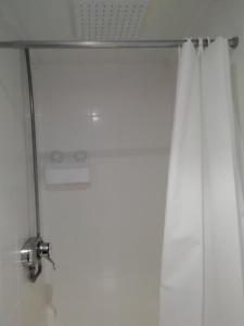 a shower with a white shower curtain and a shower head at The Penrhyn in Blackpool