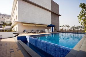 a swimming pool in front of a building at Lemon Tree Hotel, East Delhi Mall, Kaushambi in Ghaziabad