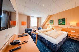 a hotel room with two beds and a desk at Dünenhotel am Meer in Warnemünde