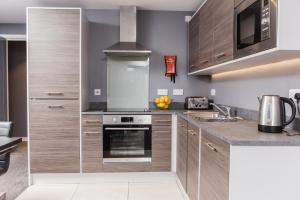 a kitchen with stainless steel appliances and wood cabinets at Dream Apartments St Thomas Hall in Belfast +37 photos