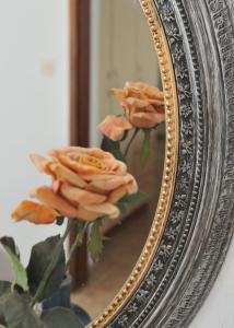 a mirror with a bouquet of orange roses at Villa Maraki in Agia Paraskevi
