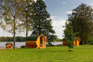a group of small wooden structures in a field next to a lake at Ezermala in Valdemārpils +54 photos