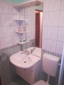 a white bathroom with a sink and a toilet at Apartmani Maruncic in Omiš