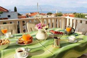 a table with a green table cloth with food and drinks at Apartments Marinović 3462 in Supetar