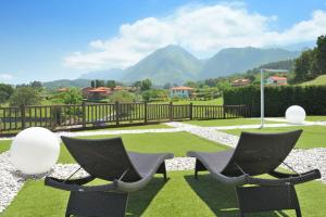 two chairs sitting on a lawn with mountains in the background at La Piconera Hotel & Spa in Ribadesella