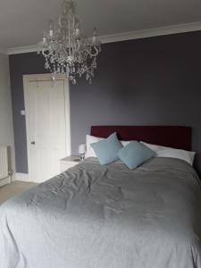 1 dormitorio con 1 cama grande y lámpara de araña en Town House Bridport Dorset, en Bridport
