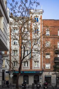 un edificio alto con un árbol delante de él en Negresco Gran Via, en Madrid