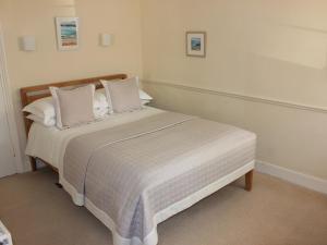 una camera da letto con letto, lenzuola e cuscini bianchi di Trafalgar House a Torquay