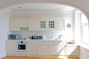 cocina blanca con armarios blancos y microondas en Sea Dreams, en Eastbourne
