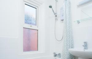 a white bathroom with a shower and a sink at MyCityHaven - 3 bedroom Shirehampton flat near Avonmouth & M4 in Bristol +17 photos