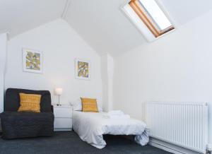 a white bedroom with a bed and a chair at MyCityHaven - Stylish & Flexible Shirehampton Apartment in Bristol