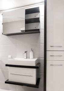 a white bathroom with a sink and a mirror at Apartament Alan in Kłodzko