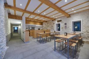 Habitación con mesas y sillas en una pared de piedra. en Albergue San Francisco, en Arzúa