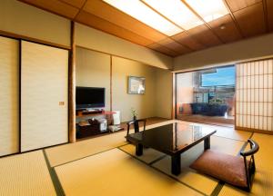 ein Wohnzimmer mit einem Couchtisch und einem TV in der Unterkunft Juhachiro in Gifu
