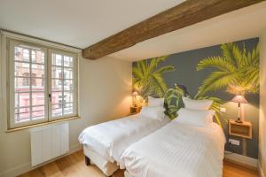 - 2 lits dans une chambre ornée d'une fresque murale de palmiers dans l'établissement La Maison de Pierre et Valérie St Leonard Honfleur, à Honfleur