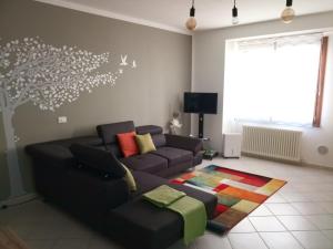 a living room with a couch and a tree mural at Bed & Bar Mini Apartment in Pontebba