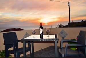a table with a bottle of wine and two glasses at Casa do Avô Ladeira in Estreito da Calheta