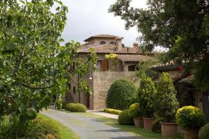 una gran casa de piedra con un camino delante de ella en Podere le Mezzelune en Bibbona