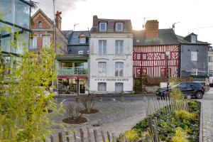 une rue de ville avec des bâtiments et une voiture garée devant dans l'établissement La Maison de Pierre et Valérie St Leonard Honfleur, à Honfleur