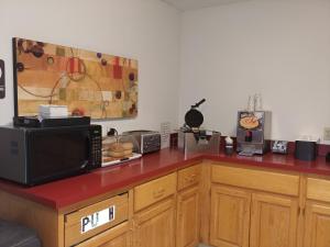 eine Küche mit einer Mikrowelle und einer roten Arbeitsplatte in der Unterkunft Americas Best Value Inn Charlotte in Charlotte