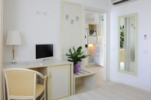 Habitación blanca con escritorio, TV y silla. en Residence Suite Smeraldo, en Riccione