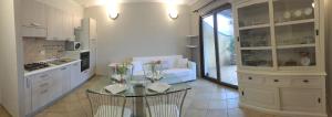 a white kitchen with a couch and a glass table at Domu de Bisu in Villasimius