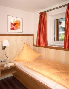 ein kleines Schlafzimmer mit einem Bett und einem Fenster in der Unterkunft Fellhornhaus Ferienwohnungen in Oberstdorf