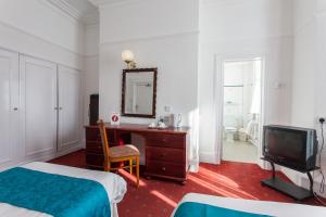 a bedroom with a desk and a mirror and a tv at Prince Of Wales Hotel in Southport