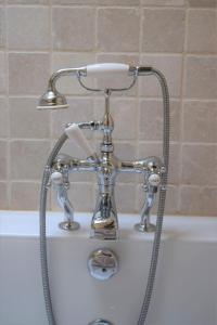 a chrome shower faucet on top of a bath tub at Oundle Bespoke Apartments in Oundle