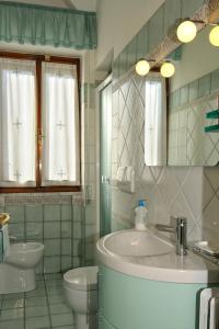Un baño con lavabo, inodoro y espejo. en Villa Elza, en Forte dei Marmi