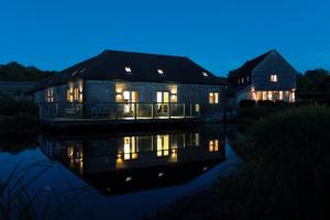 a house with lights on in the water at night at Whytings Stud Barn 1 in Horsham
