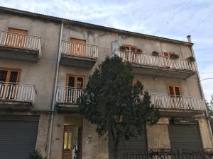 een gebouw met balkons en een boom ervoor bij La casa di Fausto in Cesarò