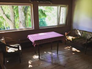 a room with a table and a couch and two windows at Valuntynė in Plokščiai