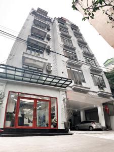 a white building with a car parked in front of it at Khách Sạn Sao in Hanoi