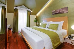 a bedroom with a large white bed with green accents at Boutique Hotel Bol in Bol