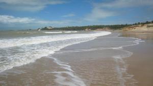 a beach with waves coming in from the ocean at Castelo Cabo de Sao Roque in Maxaranguape